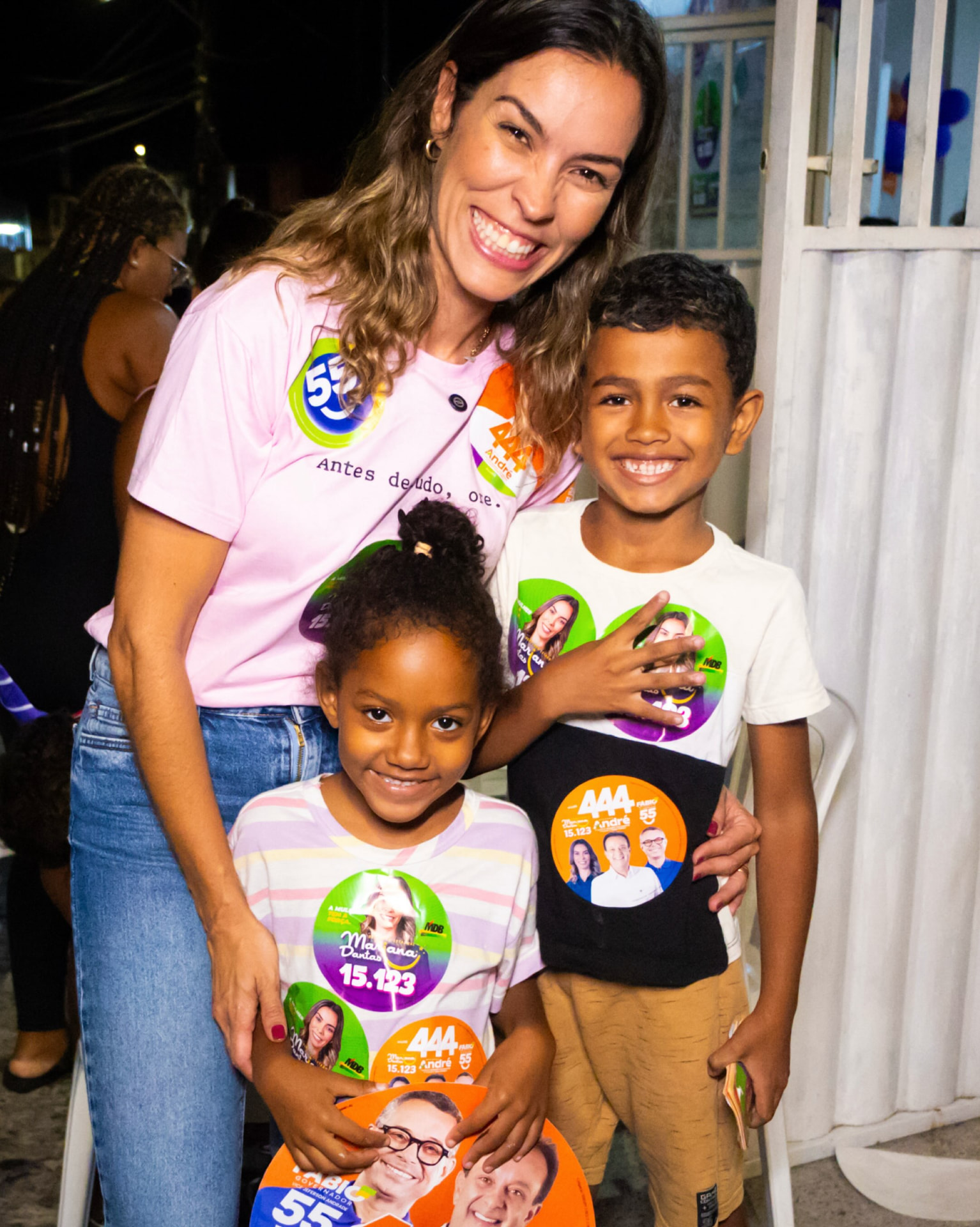 Mariana Dantas sorrindo ao lado de duas crianças durante atividade de campanha