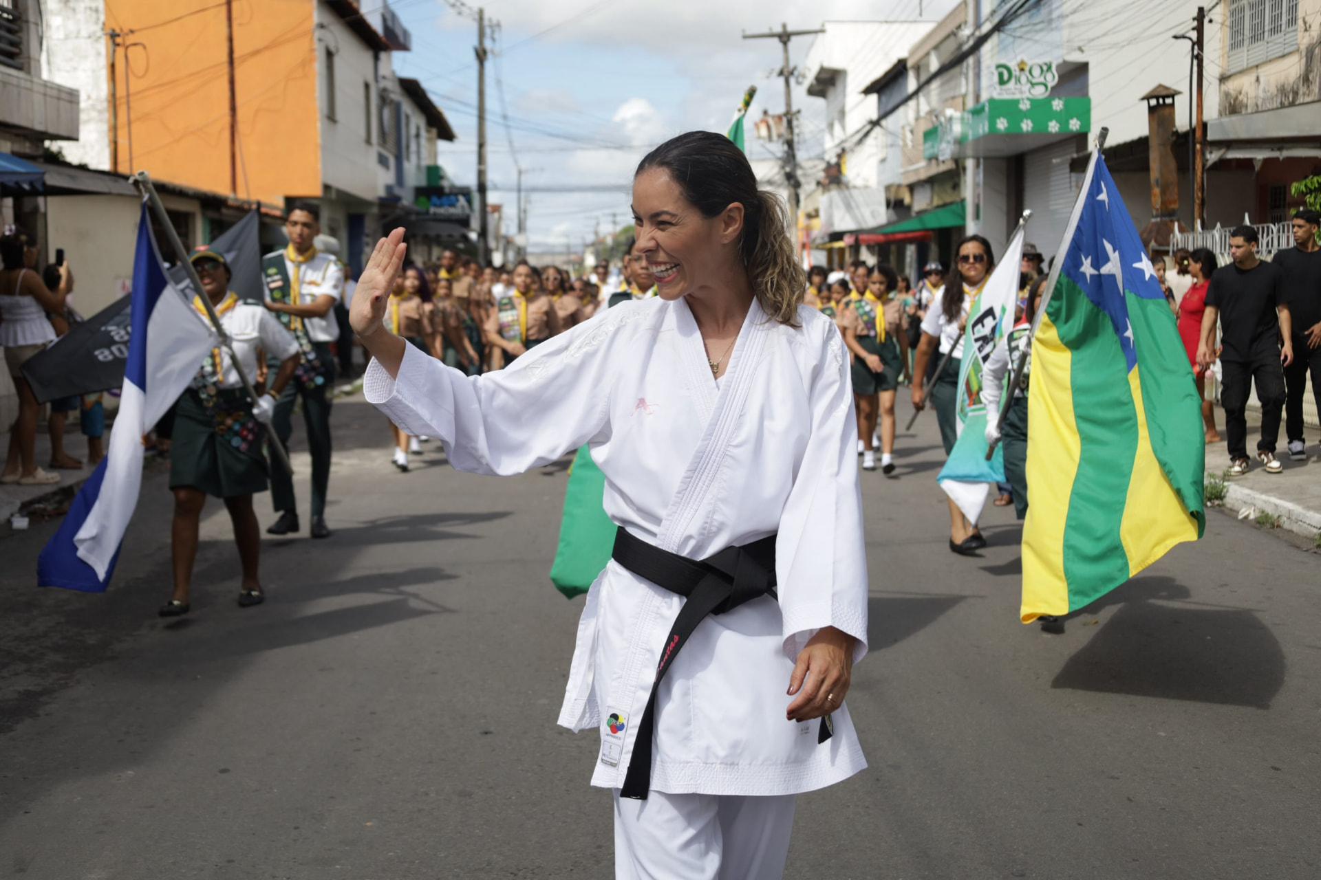 Mariana Dantas caminhando e acenando durante o desfile cívico dos Desbravadores
